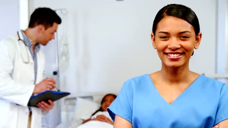 Smiling-nurse-standing-with-arms-crossed-in-hospital