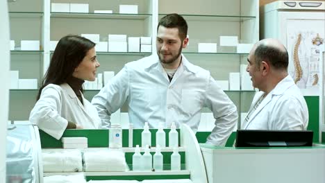 Team-of-pharmacist-chemist-woman-and-man-standing-in-pharmacy-drugstore-and-talking-positive