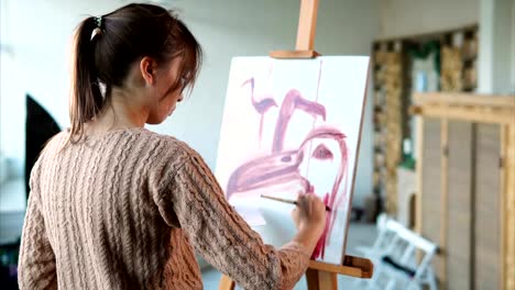 Woman-paints-swift-strokes-of-pink-flamingos-in-different-angles,-she-uses-brush