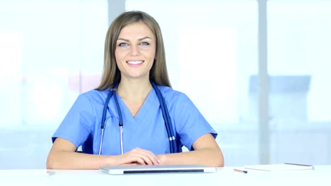 Portrait-of-Smiling-positiven-weiblichen-Arzt-sitzen-in-Klinik