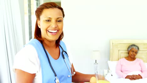 Smiling-female-doctor-serving-breakfast-to-senior-woman-on-bed-4k