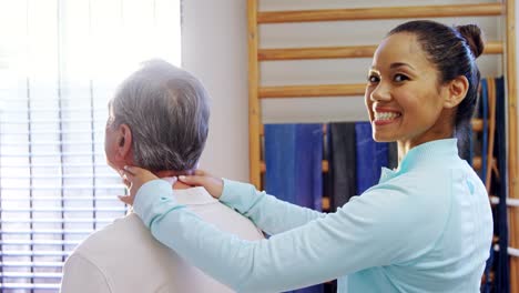 Portrait-of-happy-physiotherapist-giving-neck-massage-to-senior-patient-4k