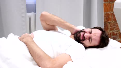 Beard-Man-with-Neck-Pain-Trying-to-Relax-in-Bed