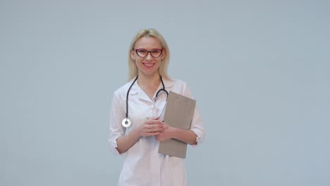 Mujer-médico-con-bata-blanca-y-estetoscopio-sonriendo-mirando-a-cámara