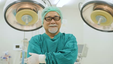 Retrato-de-senior-masculino-cirujano-usar-completo-quirúrgico-friega-cámara-sonriente-en-quirófano-en-el-hospital.