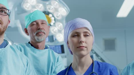 Gliding-Shot-of-Diverse-Team-of-Professional-surgeon,-Assistants-and-Nurses-Standing-Proudly-in-the-Real-Modern-Hospital-with-Authentic-Equipment.