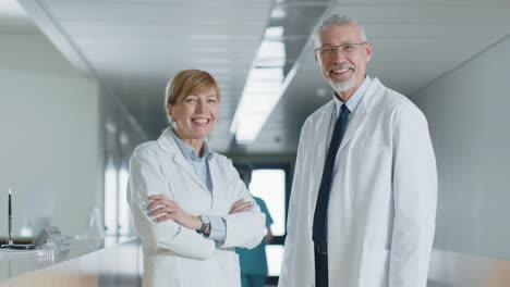 In-the-Hospital-Doctors-Standing-at-the-Reception-Desk,-having-Professional-Discussion,-and-Smiling-at-the-Camera.-Modern-Hospital-with-Patients-and-Medical-Personnel.