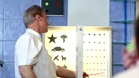 Ältere-männliche-Augenarzt-zeigen-auf-Buchstaben-der-Sehtafel