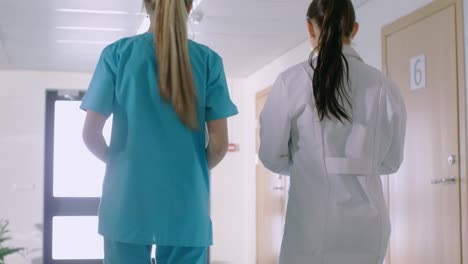 In-the-Hospital,-Back-View-Shot-of-Nurse-and-Doctor-Walking-Through-Hallway.-Hospital-Personnel-Working.