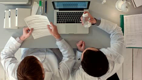 Scientists-looking-attentively-at-pill-in-hospital.-Top-view