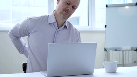 Applying-Geschäftsmann-mit-Wirbelsäule-Rückenschmerzen-im-Büro-arbeiten