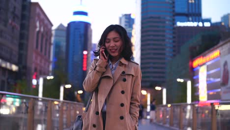 Mujer-asiática-joven-muy-feliz-hablando-por-el-teléfono-móvil-mientras-camina-en-la-calle-en-cámara-lenta