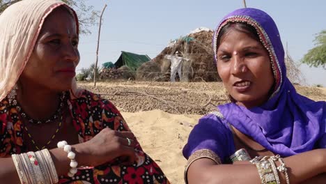 Close-up-of-friends-talking-in-front-of-their-huts-in-Rajasthan,-India