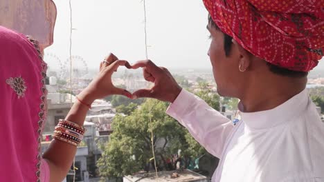 Rajasthani-couple-making-a-heart-sign-with-their-hands-overseeing-the-Pushkar-Mela-festival-in-Rajasthan,-India