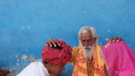 Sadhu-hindú-bendecir-a-una-pareja-recién-casada-en-vestido-tradicional,-todo-el-mundo-mirando-a-cámara