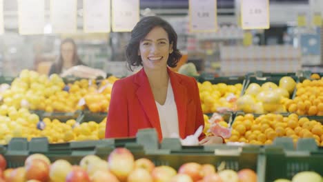 Im-Supermarkt:-Porträt-der-schönen-lächelnden-Frau-stehend-in-der-Frischwaren-Sectiomn-des-Ladens,-Bio-Obst-und-Gemüse-zu-wählen.