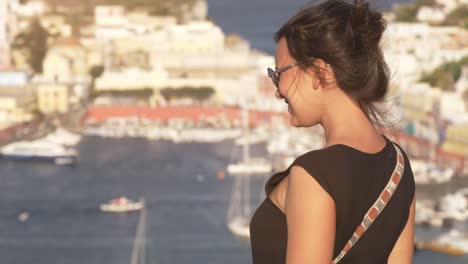 Glückliche-junge-Frau-zeigenden-Touristenort-auf-der-Insel-Ponza-in-Italien-traditionell-Meer-Stadtlandschaft