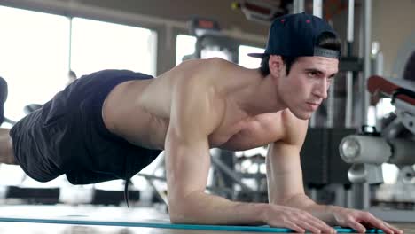 A-shirtless-guy-at-the-gym,-trains-his-body-to-stay-fit-and-have-defined-muscles.-The-athlete-raises-heavy-weights-and-fatigue.