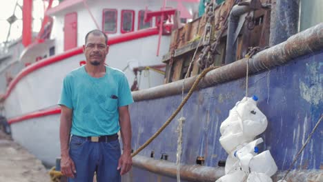 Wide-shot-portrait-of-a-middle-aged-man-of-hispanic-heritage-smiling-and-standing-next-to-a-boat-on-a-boat-dock-in-Mexico