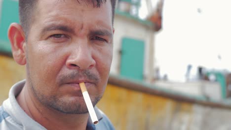 Portrait-of-a-hispanic-man-with-a-cigarette-in-his-mouth-staring-at-the-camera-on-a-boat-dock