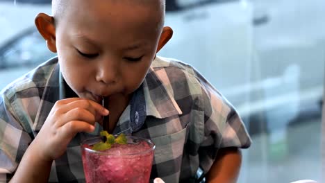 Lindo-niño-asiáticos-disfrutan-de-beber-jugo-en-el-restaurante.-Video-Slow-motion