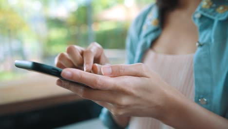 Alegre-feliz-joven-mujer-asiática-sentada-en-la-cafetería-con-smartphone-para-hablar,-leer-y-enviar-mensajes-de-texto.-Concepto-de-estilo-de-vida-de-las-mujeres.