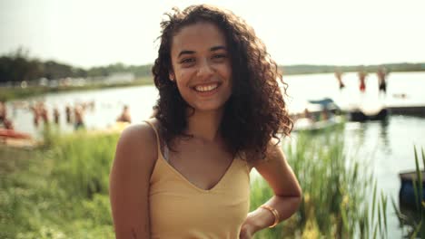 Retrato-de-mujer-joven-cerca-de-un-lago,-sonriendo.