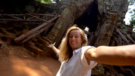 Traveling-woman-taking-selfie-portrait-in-front-of-temple's-complex-gate