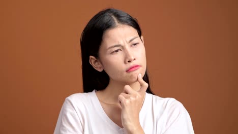 Denken-Frau-isoliert.-Porträt-von-Asiatin-im-weißen-T-shirt-denken-schwer-und-aufgeregt,-um-eine-Lösung-zu-finden,-Blick-in-die-Kamera.