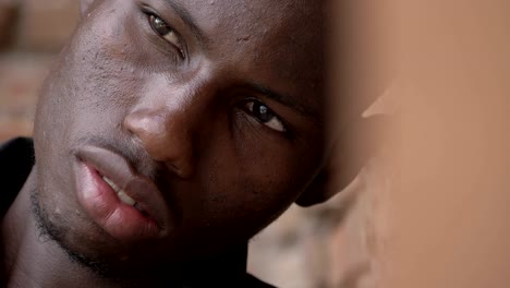 portrait-of-sad-pensive-young-black-african-man-leaning-at-the-wall