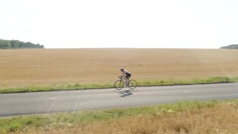 Drone-Schuss-des-Mannes-Fahrrad-zu-üben.-Luftaufnahme-des-Athleten-training-für-ein-Triatlon-Rennen,