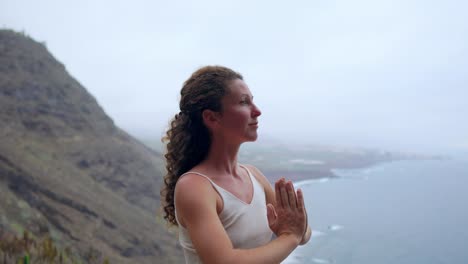 Young-woman-doing-yoga-on-a-rocky-seashore-at-sunset.-The-concept-of-a-healthy-lifestyle.-Harmony.-Human-and-nature.-The-background-of-the-blue-ocean.