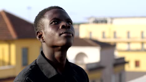 Pensive-young-african-american-man-on-the-roof,looking-up--hope,-faith