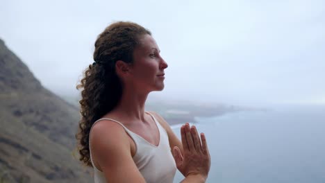 Young-woman-doing-yoga-on-a-rocky-seashore-at-sunset.-The-concept-of-a-healthy-lifestyle.-Harmony.-Human-and-nature.-The-background-of-the-blue-ocean.