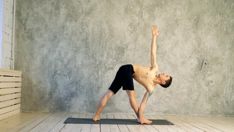 Yoga-Position-Asana-gesunde-Übung-Lebenskonzept---Mann-tut-Ashtanga-Vinyasa-Yoga-Asana-Parivrtta-Trikonasana---gedrehte-Dreieck-darstellen-indores