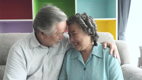 Senior-couple-sitting-and-hugging-each-other-in-living-room.