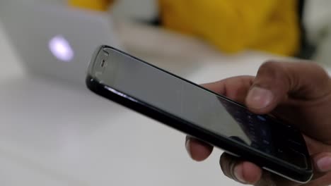 Close-up-of-brown-hands-typing-n-a-touch-screen-mobile-phone-smart-device