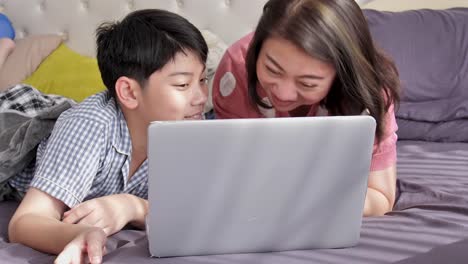 Glückliche-Familie-Mutter-und-Sohn-gerade-auf-Laptop-Computer-mit-Lächeln-Gesicht,-Slow-Motion-4K-asiatischen-Familie-Rest-auf-Bett-mit-Laptop-computer