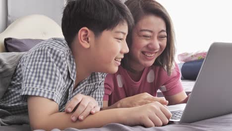 Glückliche-Familie-Mutter-und-Sohn-gerade-auf-Laptop-Computer-mit-Lächeln-Gesicht,-Slow-Motion-4K-asiatischen-Familie-Rest-auf-Bett-mit-Laptop-computer