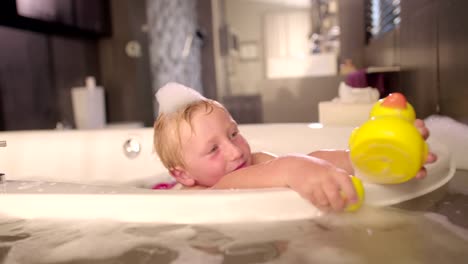 Niño-pequeño-jugando-con-caucho-Patitos-en-baño-de-burbujas