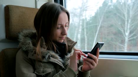 Nachdenkliche-Frau-im-Zug-unterwegs-und-per-smartphone