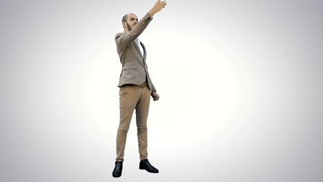 Young-man-in-suit-taking-selfies-on-the-phone-on-white-background