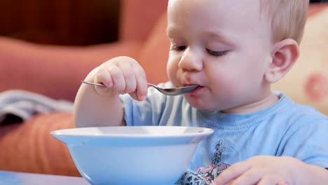 Un-atractivo-chico-de-2-años-de-edad-es-comer-sopa-roja-sí-mismo.-Cuchara-y-las-manos-fluyendo-líquido.-El-concepto-de-alimentación-saludable-de-los-niños