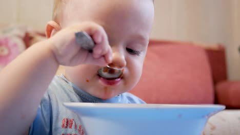 Eine-attraktive-junge-2-Jahre-alt-ist,-rote-Suppe-selbst-essen.-Löffel-und-Händen-fließt-Flüssigkeit.-Das-Konzept-einer-gesunden-Ernährung-von-Kindern