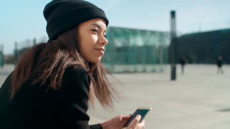 Portrait-of-young-African-American-woman-using-phone,-outdoors.