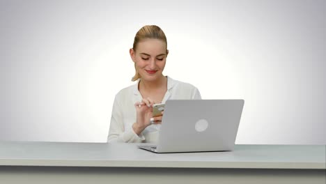 Happy-woman-is-dancing-on-her-own-using-smartphone-at-work-place-on-white-background