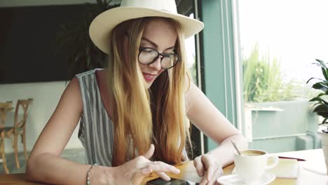 Schöne-junge-Frau-arbeitet-an-Smartphone-im-Café.-Frau-mit-app-auf-dem-Handy-und-lächelnd.