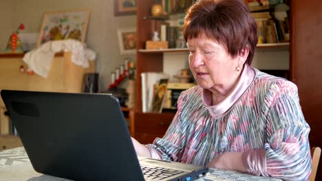 An-older-woman-checks-the-messages-on-social-networks-on-a-laptop-at-home.-She-sits-at-the-table