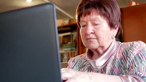 An-older-woman-checks-the-messages-on-social-networks-on-a-laptop-at-home.-She-sits-at-the-table