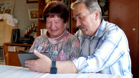 An-elderly-couple-communicates-with-their-grandchild-by-video-linking-the-tablet.-A-man-and-a-woman-are-talking-to-relatives